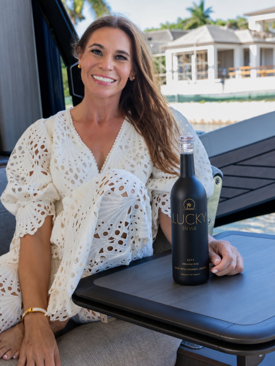Noel King, founder of Lucky Wine Group, seated aboard a boat on the Naples, Florida waterfront with a bottle of Lucky En Vue Grenache Rosé.